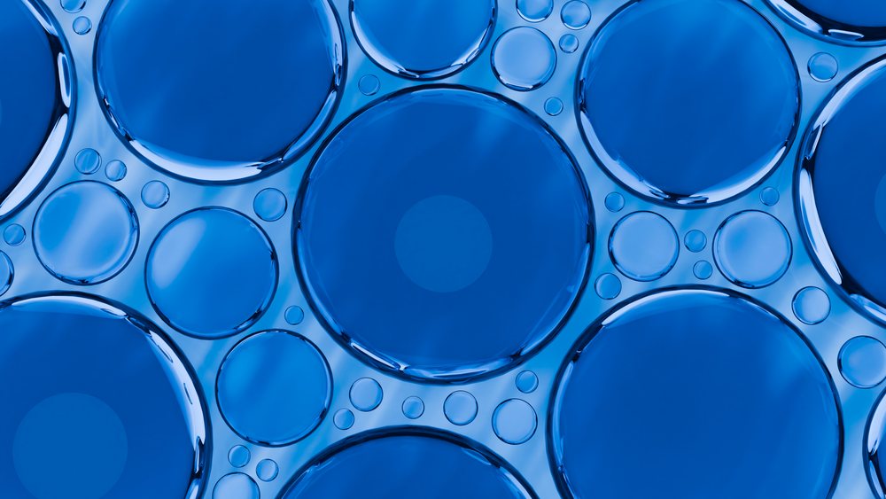 Close-up view of blue liquid bubbles forming circular patterns on a transparent surface.