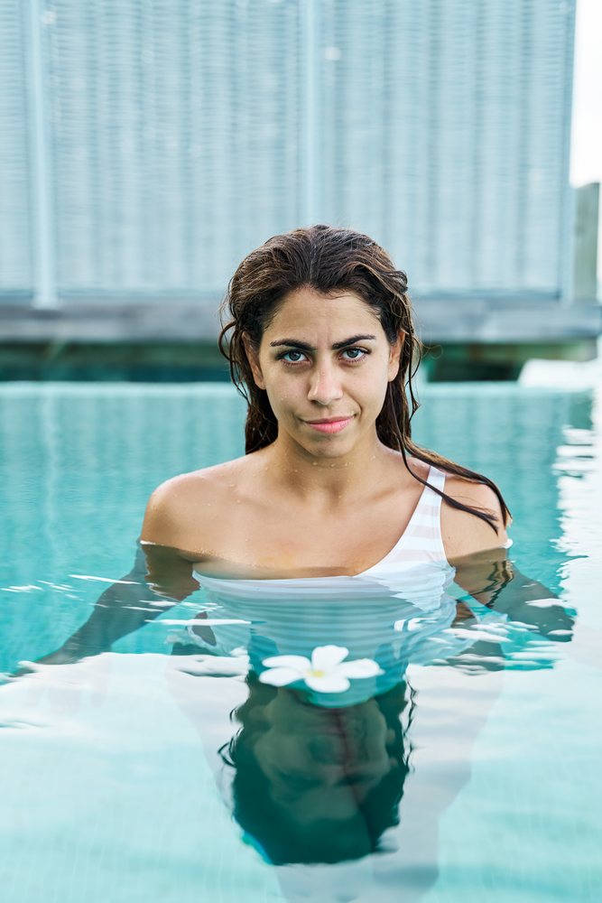 A white woman enjoys a tranquil swim with a flower in a pool