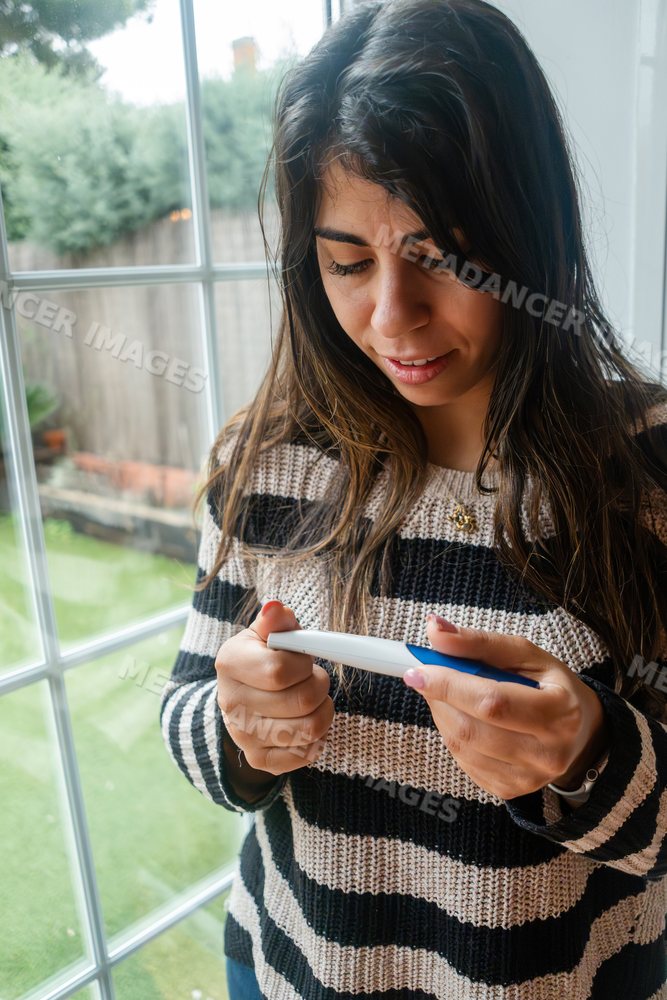 Young white woman holding a test device and looking