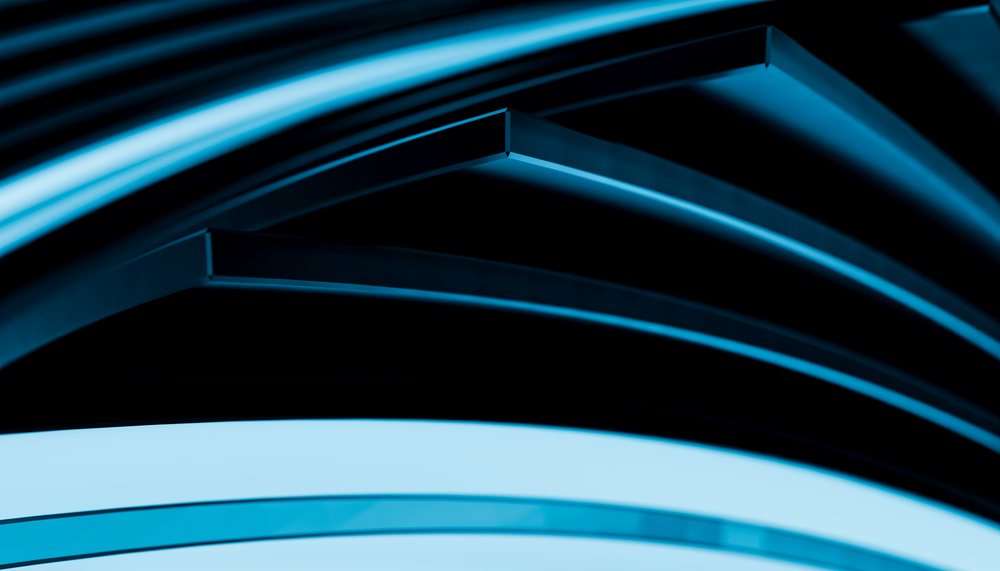 Abstract modern curved blue light shapes forming a smooth geometric pattern with reflections.