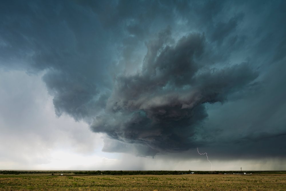 Supercell storm with lightning and dark clouds over a rural field during Storm Chasing, Weather, Environmental, Byers, Colorado, USA.