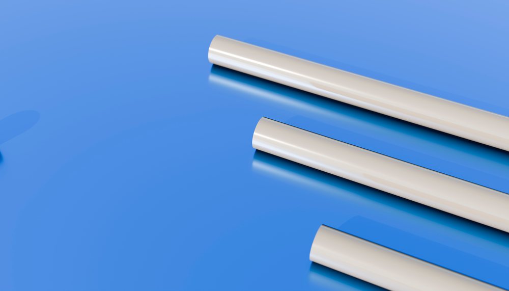 Three white cylindrical plastic tubes placed horizontally on a glossy blue surface reflecting their shapes.