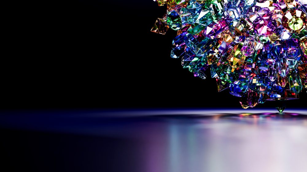 Colorful faceted crystal gemstone cluster reflecting multicolor light on a glossy surface with black background.