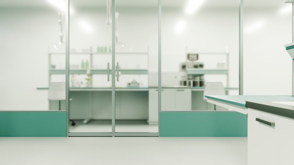 Modern laboratory workspace with glass doors, shelves holding scientific equipment, and chairs in a clean interior setting.