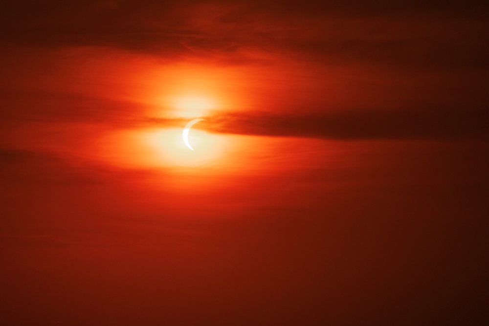 Solar eclipse with crescent sun shape visible in the red morning sky over, Landscape, Lifestyle, Valldemossa, Mallorca, Spain.