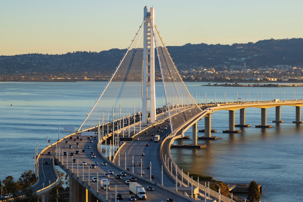 Bay Bridge carrying traffic over water with San Francisco cityscape and hills visible at sunset, City, Cityscapes, City Life, California, USA.