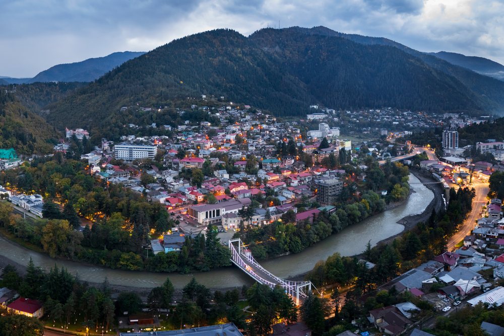 Dawn over Borjomi in Georgia shows a river with a bridge.
