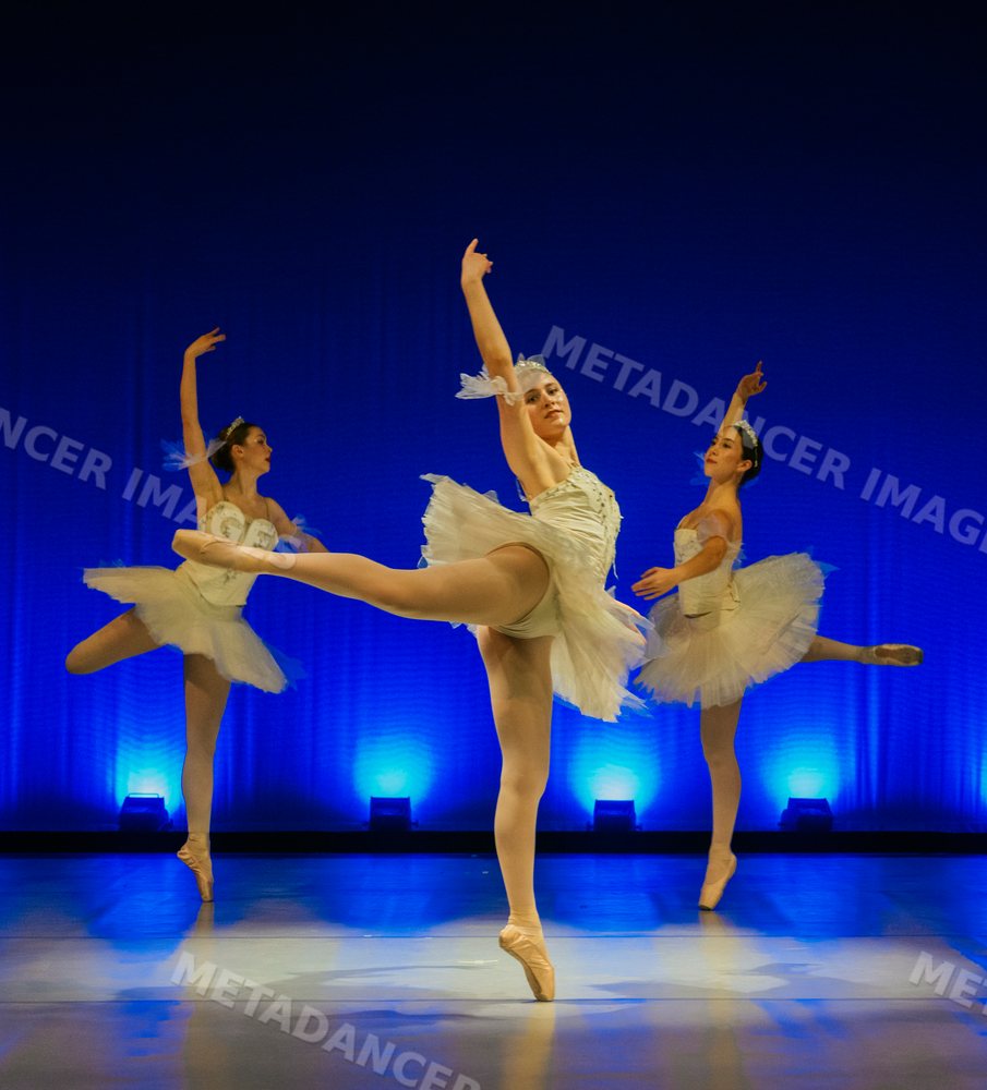 Three ballet dancers perform a classical dance on stage