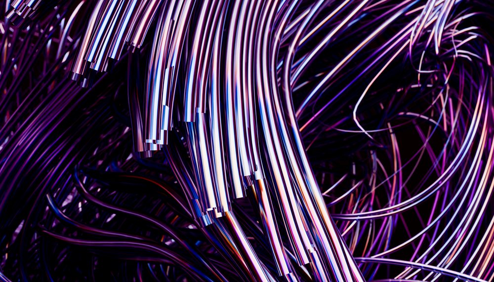 Curved shiny metal tubes illuminated with blue and purple light form an abstract industrial pattern.