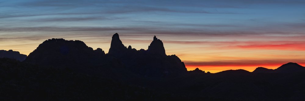Silhouette of Mule Ears rock formation with colorful Sunrise sky over desert terrain in Big Bend National Park, landscape, wildlife, Texas, USA.
