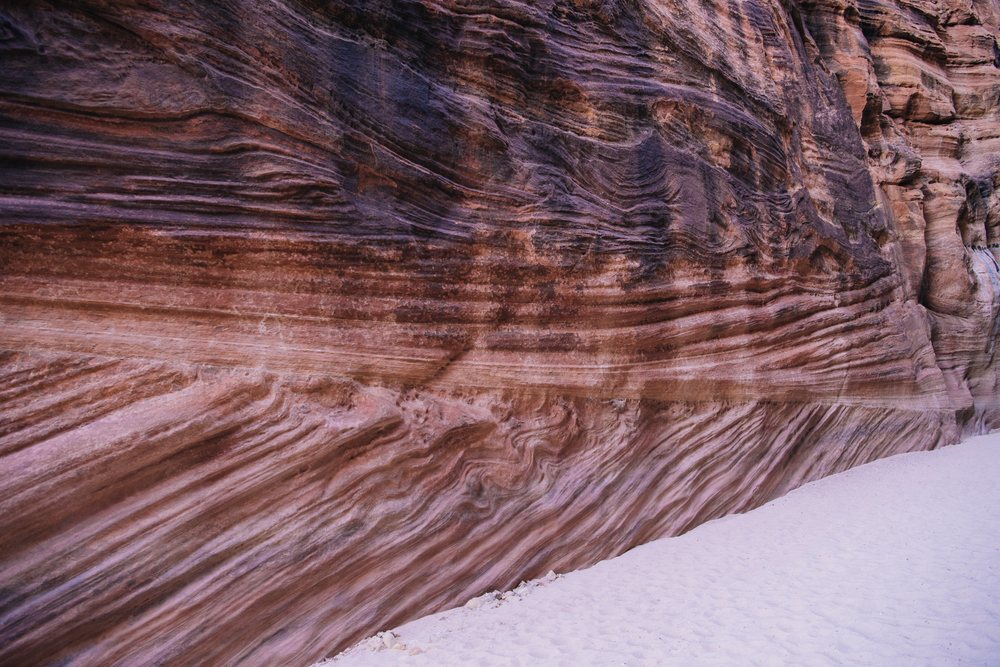 Sand covers the ground with stratified rock walls showing layered erosion patterns slot canyon, Buckskin Gulch, Utah, USA.