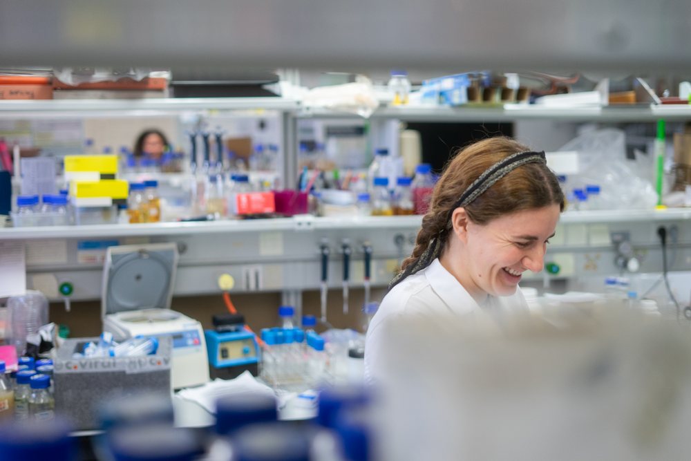 Smiling woman scientist wearing a lab coat works with scientific equipment and test tubes in a research laboratory in Seville, Andalucía, Seville. Andalucía.