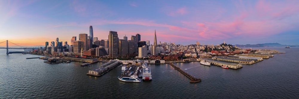 Dawn over San Francisco skyline includes Pier 14 waterfront, Bay Bridge, Coit Tower, and Alcatraz Island with a pink and purple sky, landscape, cityscape, city life, California, USA.