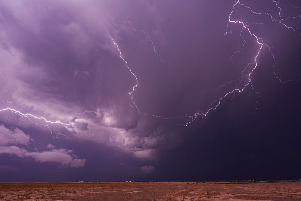 Lightning bolts illuminate a thunderstorm with dark clouds over dry open land, within Tornado Alley, Storm Chasing, Weather, Environment, USA, Midwest.