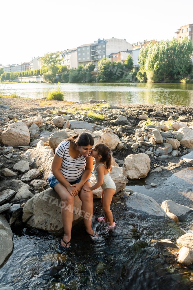 Pregnant white woman enjoys a loving moment with her child by a river