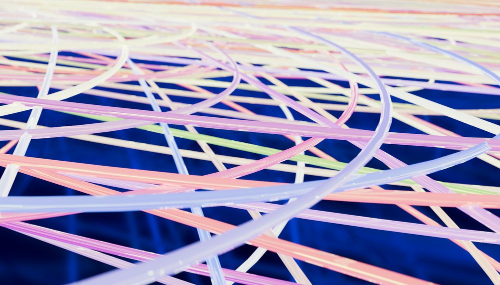 Close-up of colorful glowing fibers intertwined over a dark blue background in an abstract pattern.
