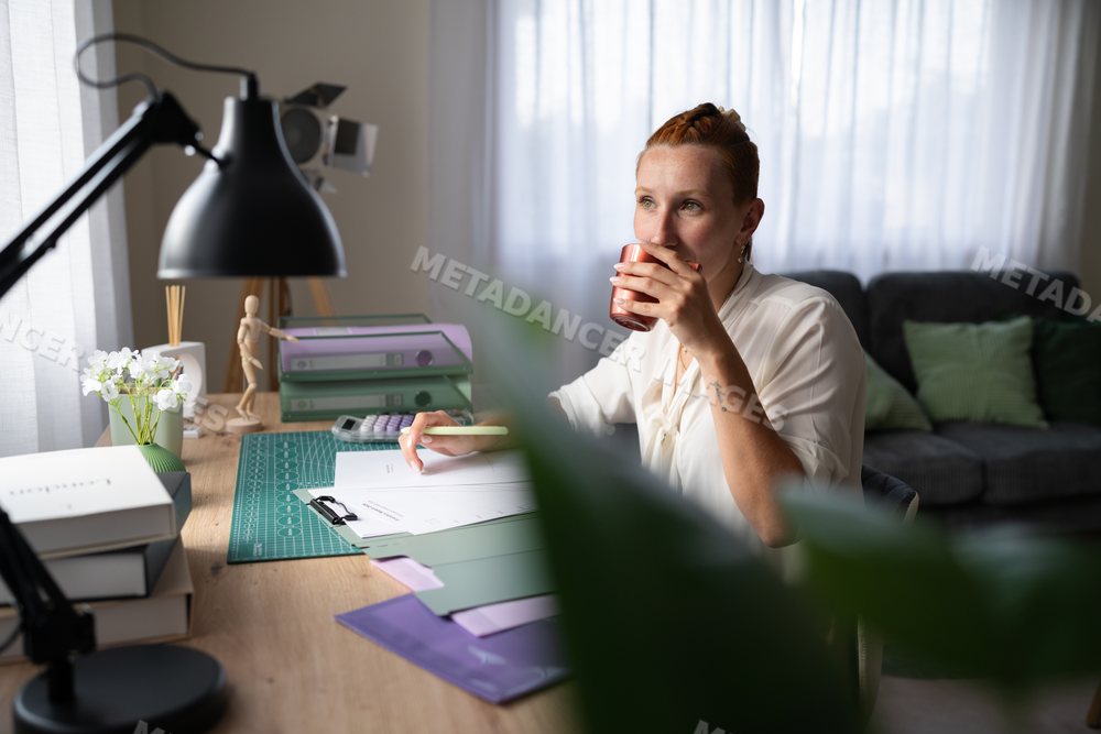 White Woman working remotely drinks coffee in a home office in Galicia