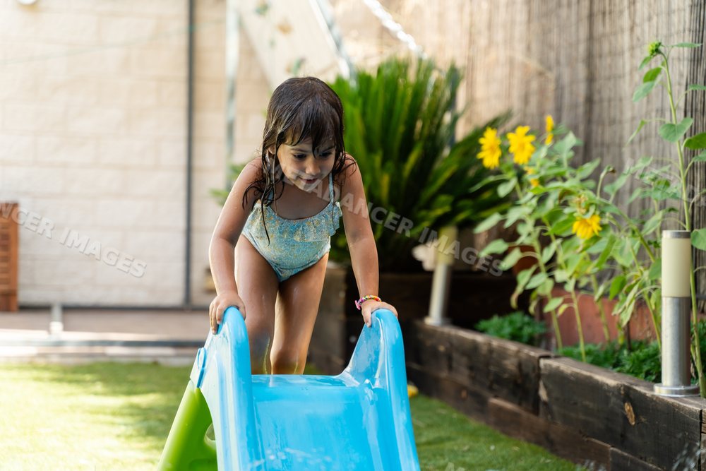 Young white girl climbing a blue water slide