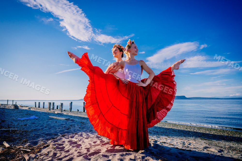 Two white women doing partner acrobatics yoga on a beach in WA, USA