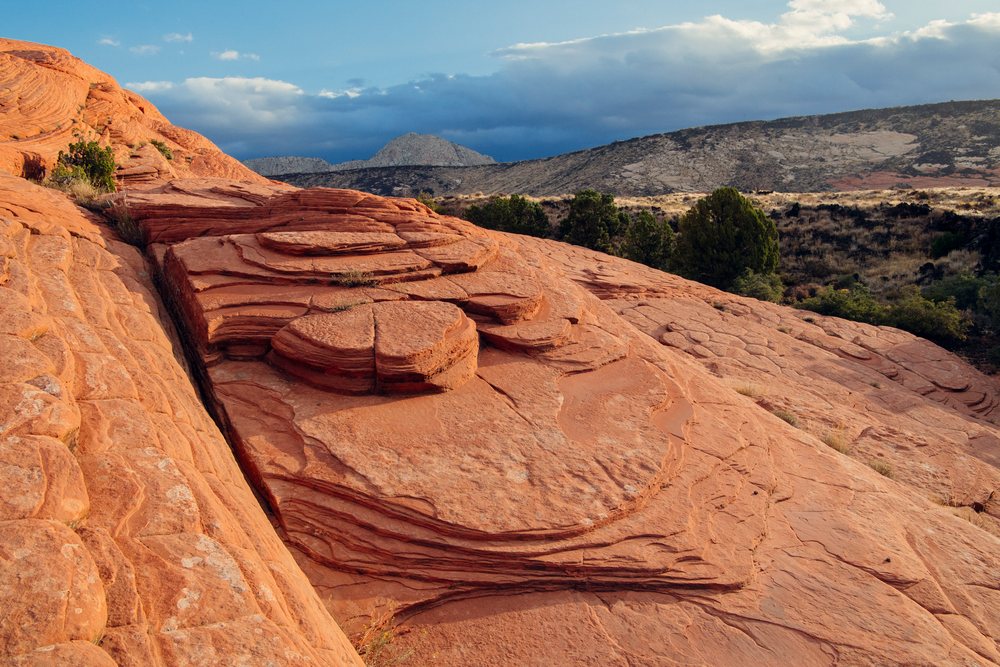 Red layered sedimentary rock formation in the desert landscape of State Park, under a partly cloudy sky, Snow Canyon, red Cliffs Desert, Utah, USA.