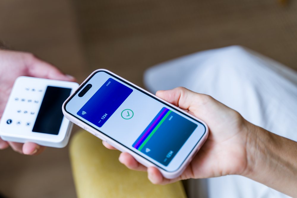 Mobile phone held near a payment terminal enables a contactless digital wallet transaction at checkout, Spain.