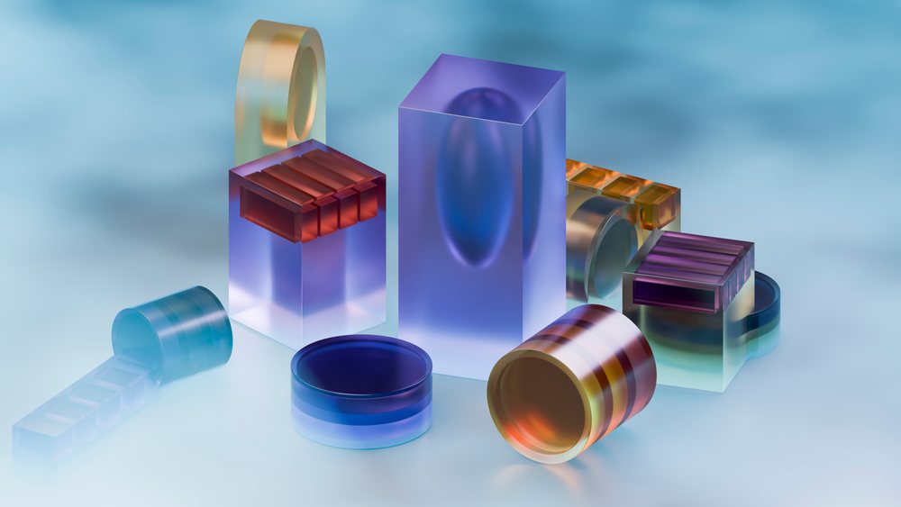 Colorful translucent geometric blocks including rectangular and cylindrical forms arranged on a smooth blue surface with light reflections.