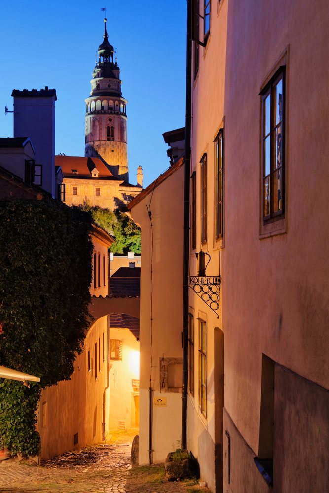 Cesky Krumlov historic tower with spire and cobblestone street lit by evening light, Bohemia, Czech Republic.
