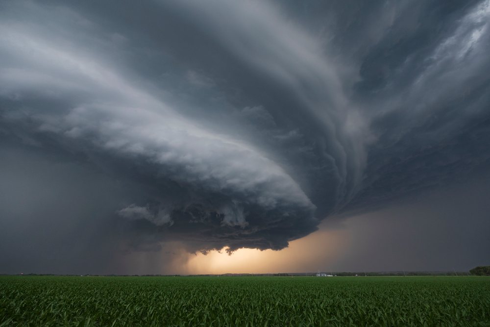 Supercell thunderstorm with tornado warning and dramatic cloud formation over green field at Sunset, Storm Chasing, Ord, Nebraska, USA.