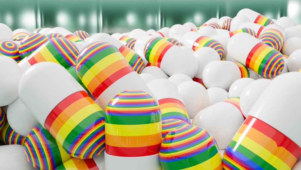 Close-up view of a pile of white pharmaceutical capsules with rainbow stripes showing glossy surfaces.