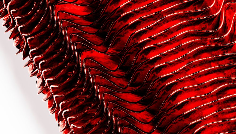 Red wavy metallic surface with reflective abstract patterns illuminated in studio lighting.