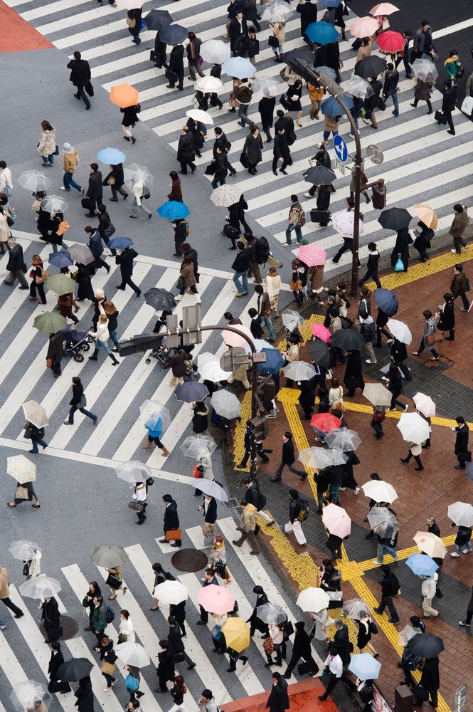 Crowd of pedestrians crossing Shibuya Crossing with umbrellas on a rainy day, Tokyo, Japan.
