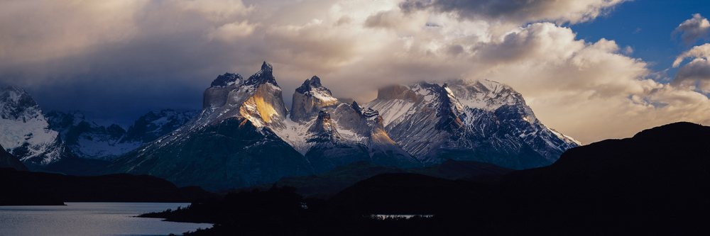 Los Cuernos mountains rise dramatically above Lake Pehoe under a moody cloudy sky, Chile.