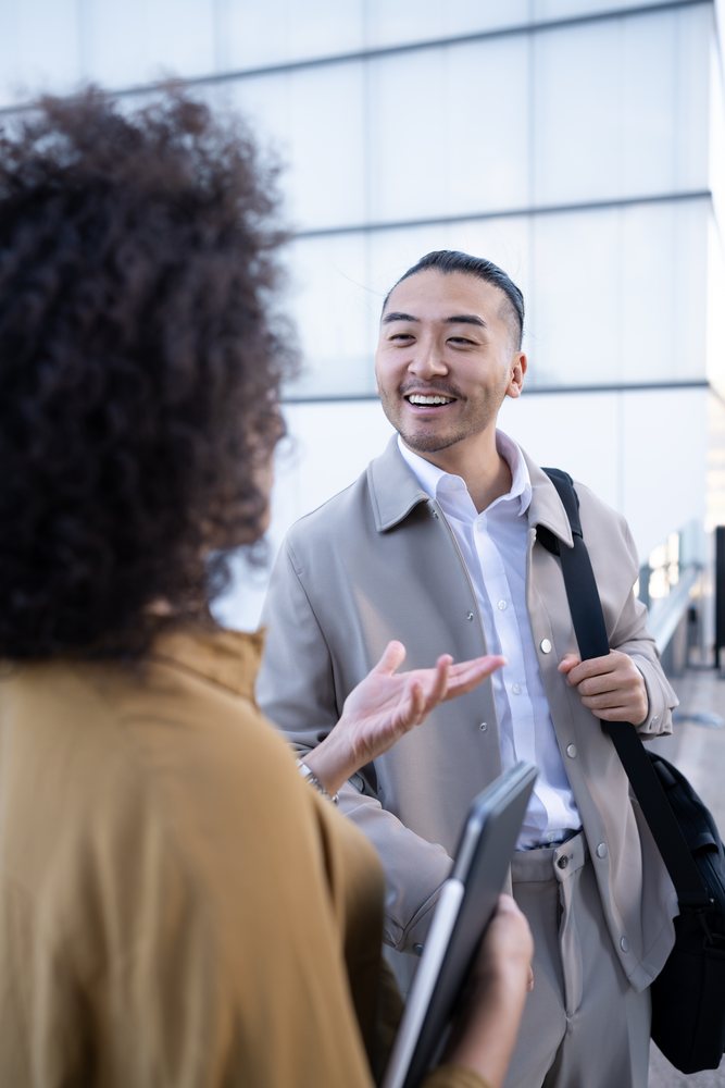 Man and woman having a friendly conversation outdoors near a modern office building, Madrid, Spain.