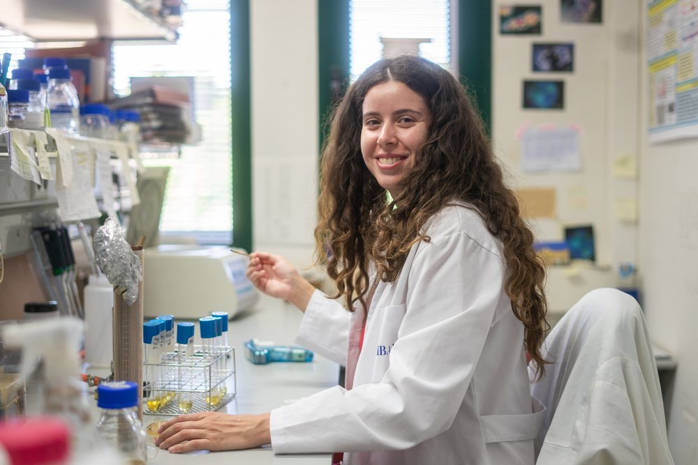 Smiling female scientist in a white lab coat works with test tubes in a biology research laboratory, Seville, Andalucía.