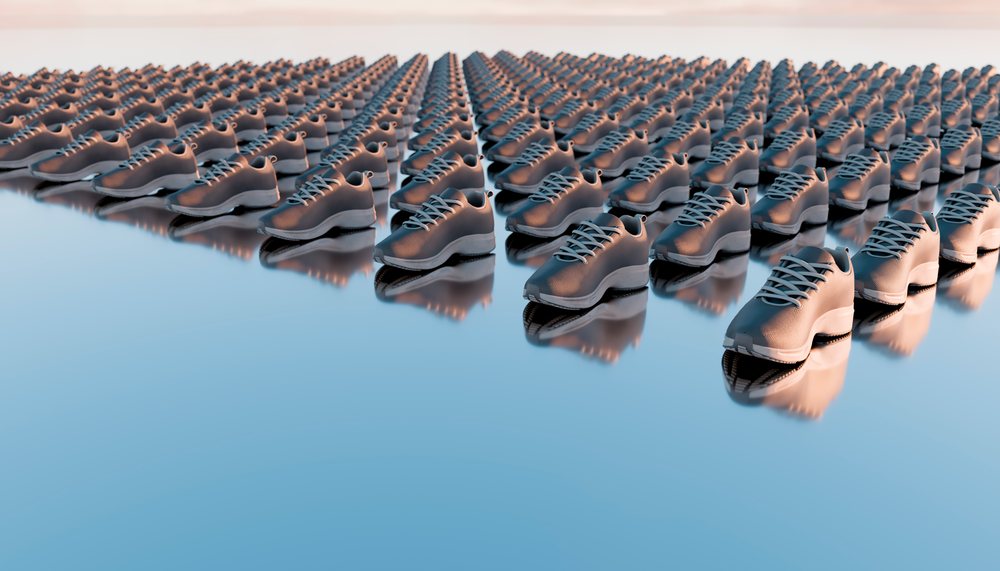 Rows of running shoes arranged on a reflective blue surface, creating a pattern and repetition effect.