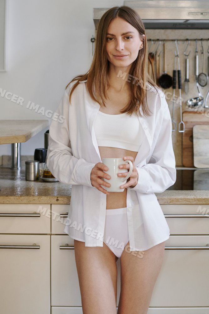 A young white woman holds a mug in a kitchen in Germany