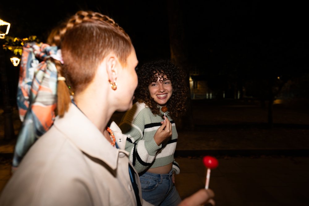 Two friends walking at night in Santiago De Compostela enjoying lollipops and conversation, friendship, Spain.