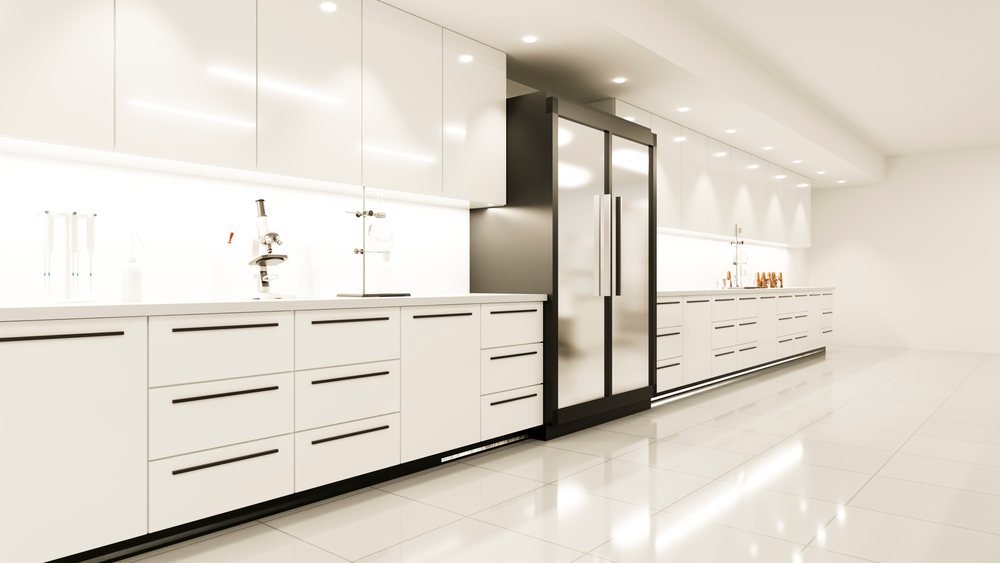 Modern spacious kitchen with white cabinets, double door refrigerator, and laboratory equipment on clean countertops.