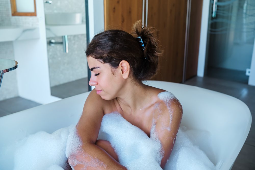 A woman relaxes in a bubble bath in a modern bathroom in the, Maldives.