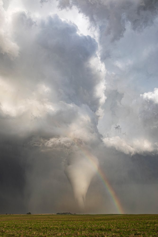 Tornado funnel cloud forms under storm clouds with a Rainbow arching over a flat green field, Dickens, Nebraska, USA.