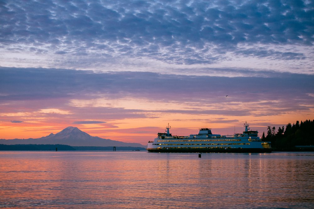 Seattle ferry cruising on water at sunset with Mount Rainier visible in the background, Bainbridge Island, WA, USA.