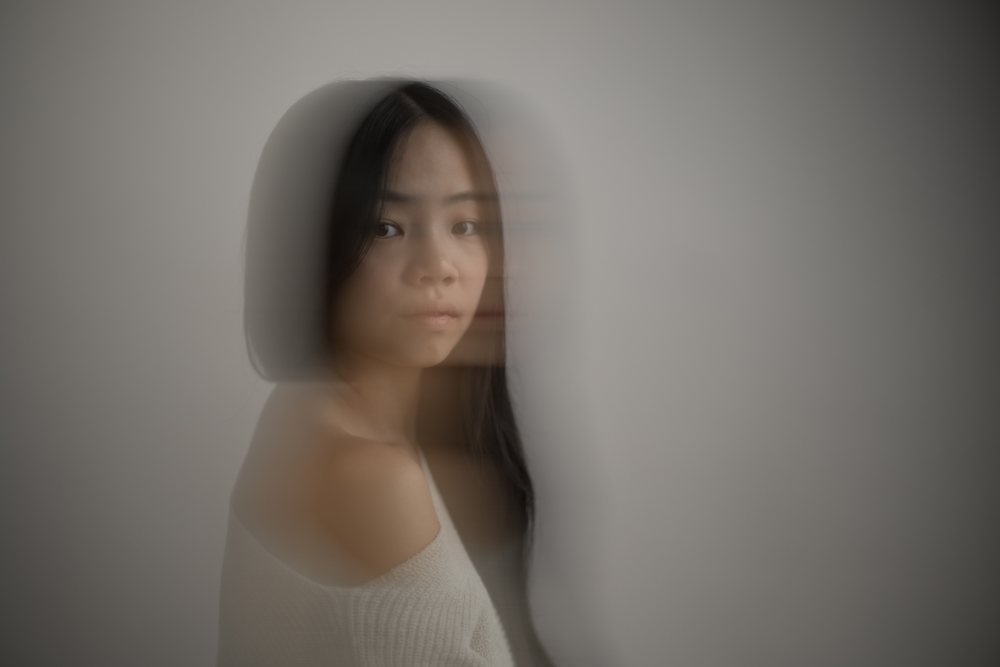 Portrait of a young Asian woman with motion blur effect in an indoor studio, conveying a serene and contemplative mood, Art, emotional.