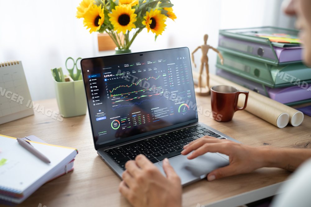 A white person analyzing stock market data on a laptop