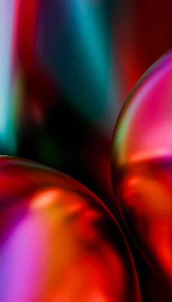 Abstract colorful glossy spheres with smooth reflective surfaces against a blurred blue background.