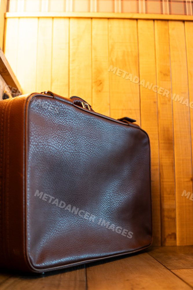 Brown leather vintage briefcase resting on wooden floor against