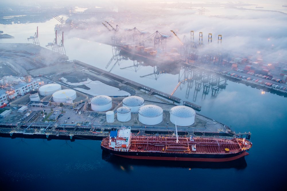 Oil tanker docked near oil storage tanks at a major port in foggy conditions, major port, CA, USA.