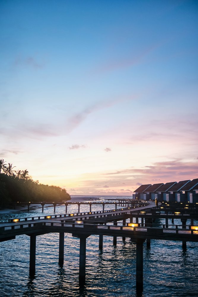 Wooden walkways linking overwater bungalows at sunset in the Maldives