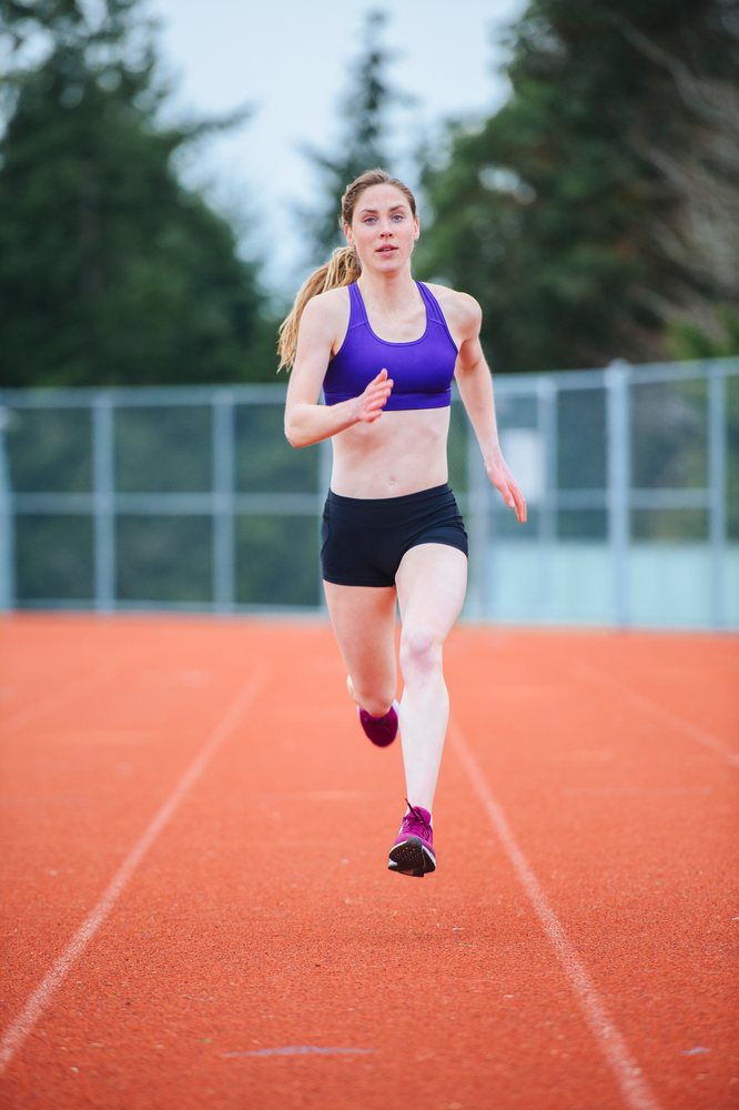 Female athlete running swiftly on an outdoor athletics track at a stadium, USA.