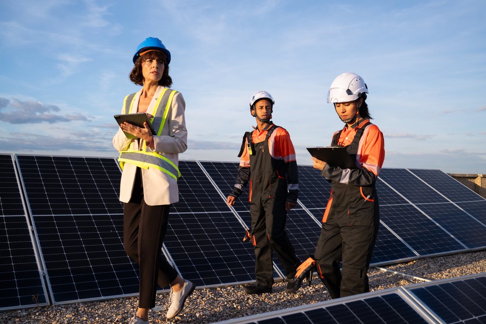 Solar energy technicians and engineer inspect solar panels at a solar farm during daylight, Madrid, Spain.