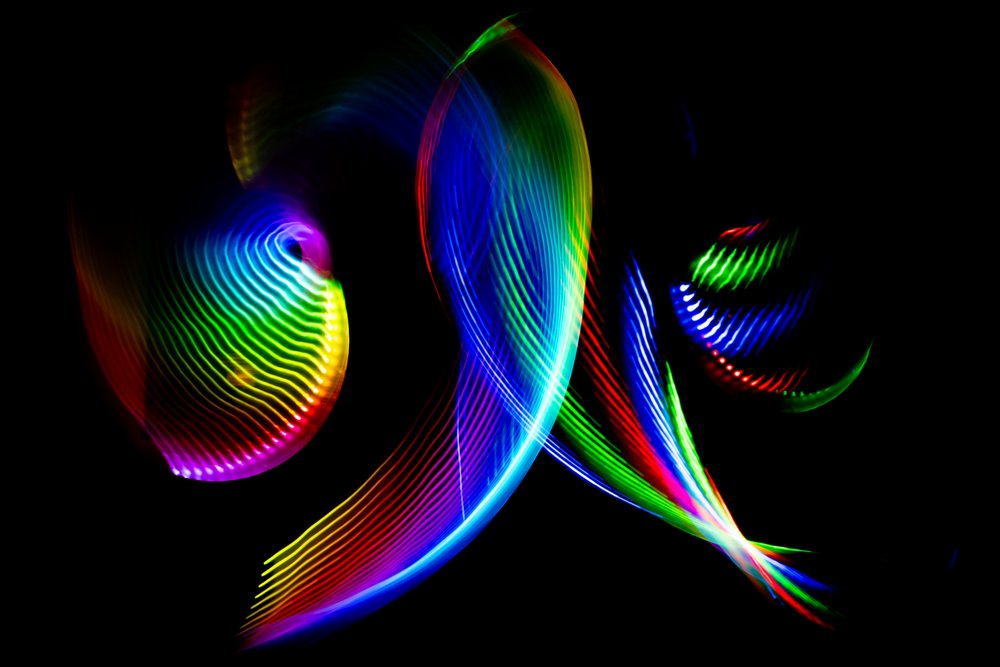 Abstract colorful swirling LED light trails captured with long exposure on a black background.